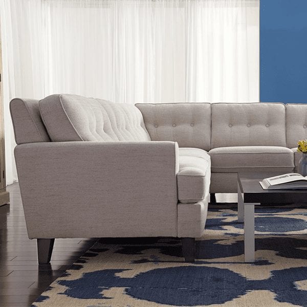 Light grey, upholstered, 5 cushion, tufted back sectional with squared arm rests.