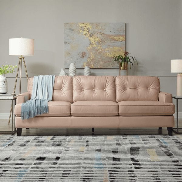 Light pink, leather, 3 cushion, sofa with button tufting, low track arms and tapered wooden legs.