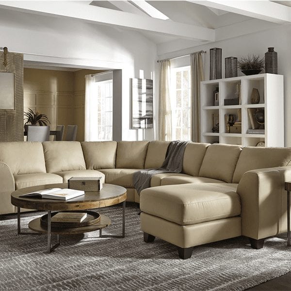 Beige, leather, 6 cushion sectional subtle curved arms and chaise on right side.